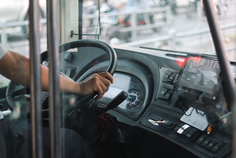 Een buschauffeur die passagiers veilig vervoert in Zwolle, met een mooie achtergrond van de stad en bussen.